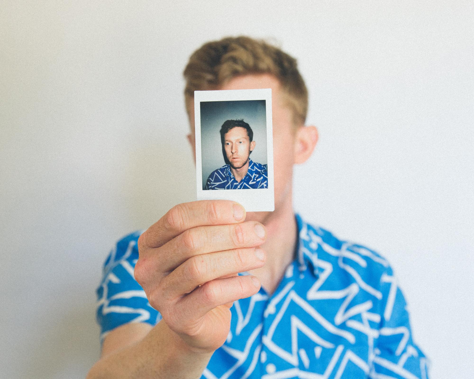 Man holding up a passport photo to his face